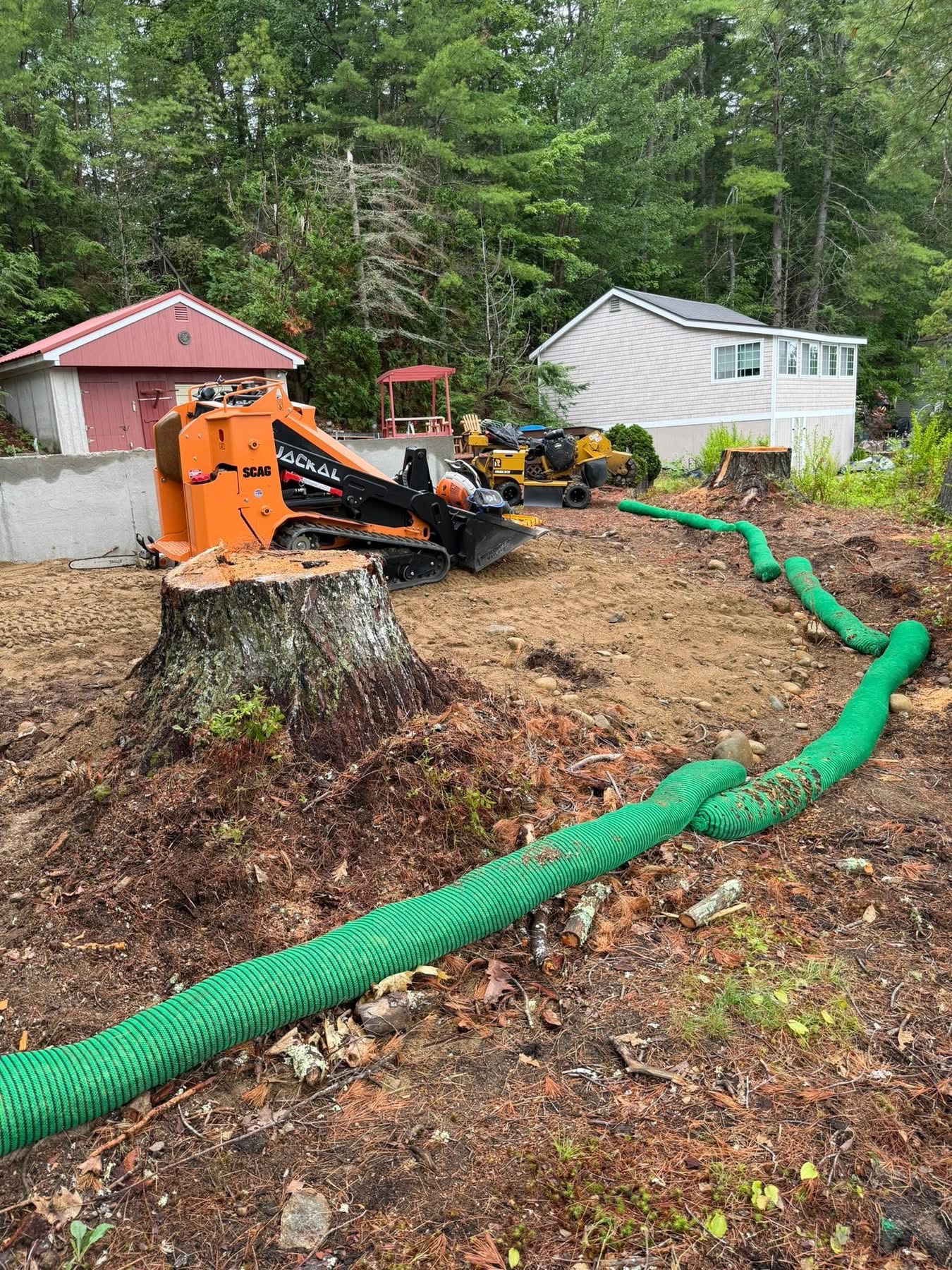Stump grinding job site with erosion control socks and equipment