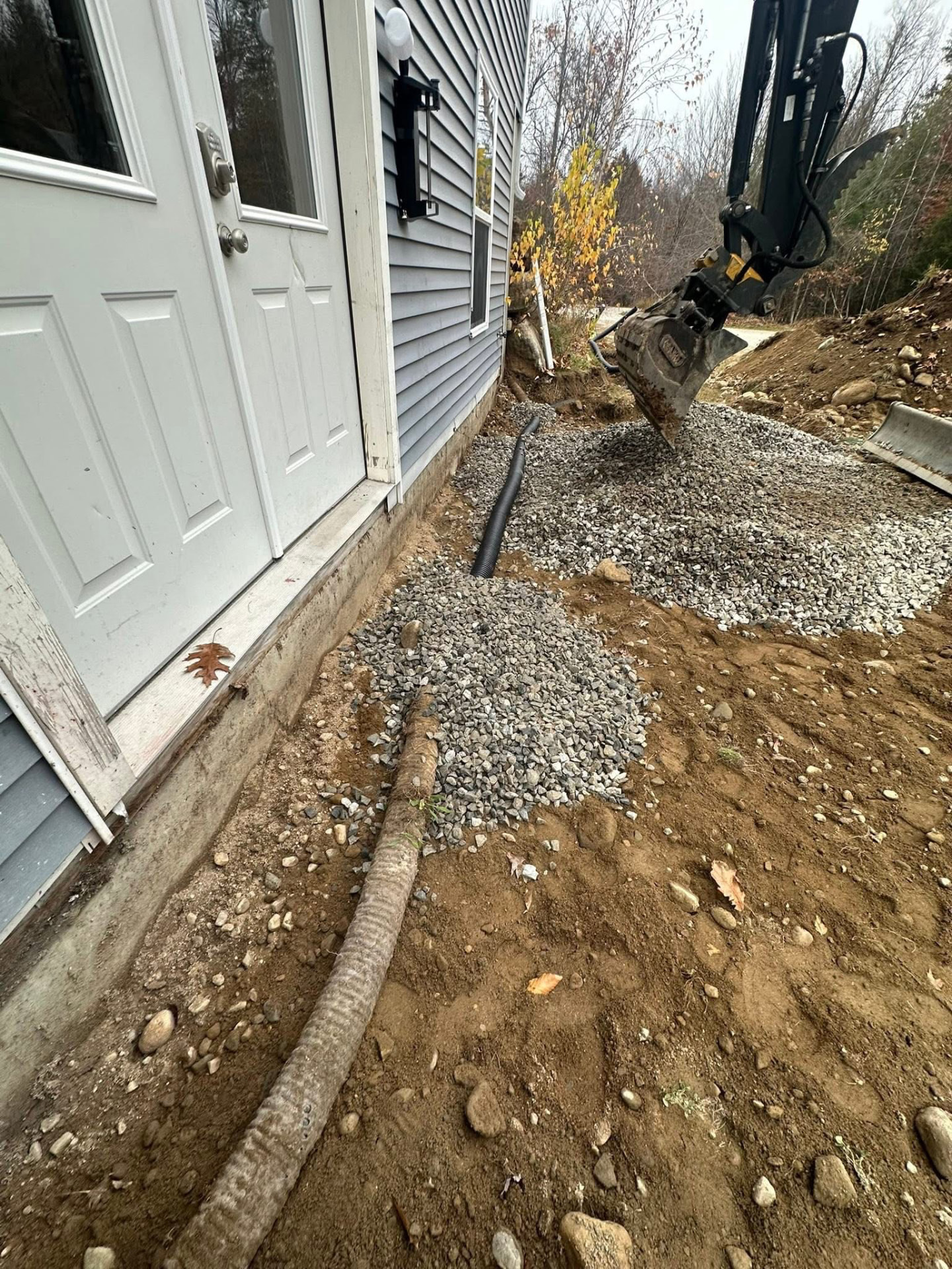 Gravel base and drain line being installed beside a house